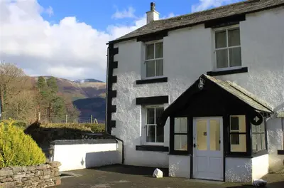 a white and black house with a white door at Pen Cottage in Keswick