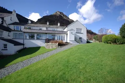 a large white house with a hill in the background at Pen Cottage in Keswick