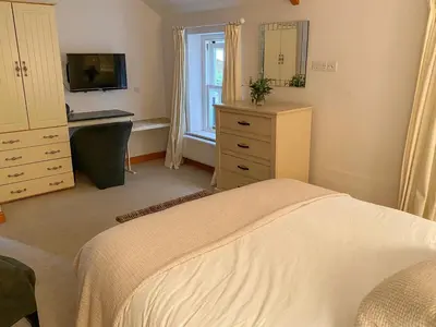 a bedroom with a bed and a desk and a television at Dove Holme Cottage in Grasmere