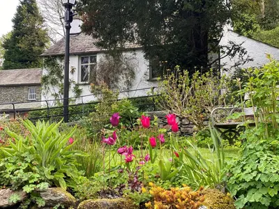 a garden with pink flowers in front of a house at Dove Holme Cottage in Grasmere