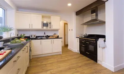 a large kitchen with white cabinets and black appliances at Lanterns At Grasmere in Grasmere