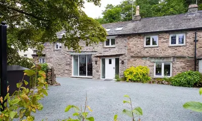 a stone house with a driveway in front of it at Underhowe in Grasmere
