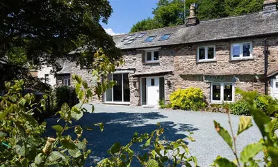 a stone house with a driveway in front of it at Underhowe in Grasmere