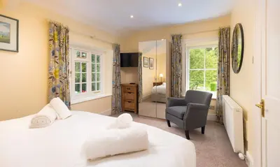 a bedroom with a bed and a chair and a window at Scots Pine in Keswick