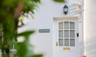 a white house with a door and a sign on it at Scots Pine in Keswick