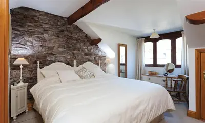 a bedroom with a large white bed and a stone wall at High Raise in Grasmere