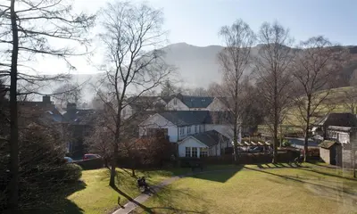 a group of houses and trees with mountains in the background at High Raise in Grasmere