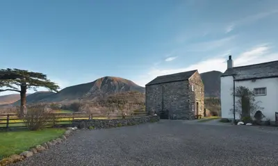 an old stone building with mountains in the background at Cedar Nook in Loweswater
