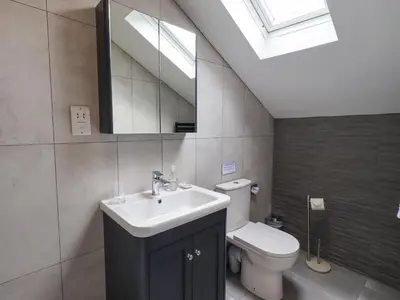 a bathroom with a sink and a toilet and a mirror at The Smithy in Borrowdale Valley