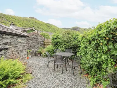 a patio with a table and chairs in a garden at The Smithy in Borrowdale Valley