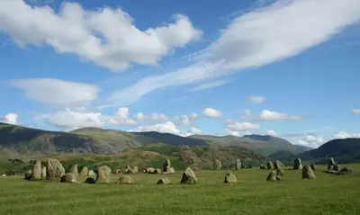 a field with rocks in a field with mountains at The Smithy in Borrowdale Valley