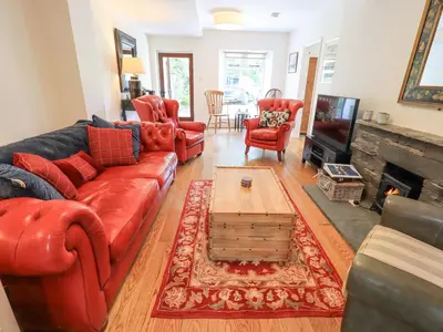 a living room with a red couch and a fireplace at Rowan Cottage in Grasmere