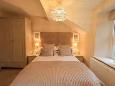 a bedroom with a large bed and a chandelier at Honeywood House in Grasmere