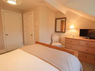 a bedroom with a bed and a dresser with a television at Honeywood House in Grasmere