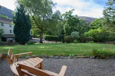 two wooden benches sitting in a yard with a lawn at Swinside Cottage in Keswick