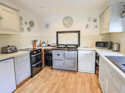 a kitchen with white cabinets and a wooden floor at Rawfell in Ambleside
