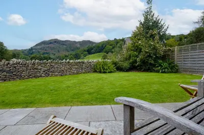 a yard with a bench and a stone wall at The Old Police House in Grasmere