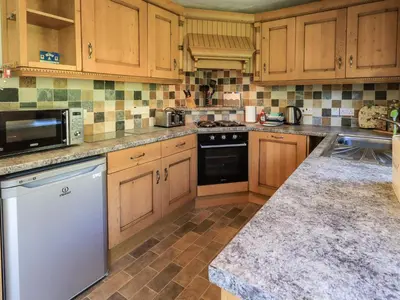 a kitchen with wooden cabinets and a stove top oven at Bleaberry Cottage in Penrith