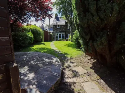 a garden with a stone walkway in front of a house at Bleaberry Cottage in Penrith