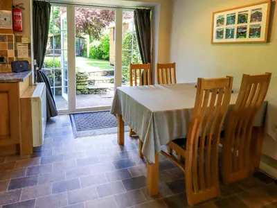 a dining room with a table and chairs and a kitchen at Bleaberry Cottage in Penrith