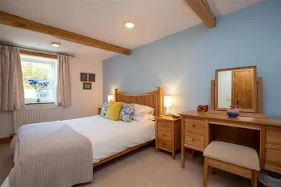 a bedroom with a bed and a dresser and a mirror at Cygnet Cottage in Keswick