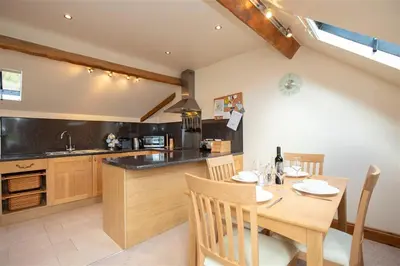 a kitchen with a wooden table and a dining room at Cygnet Cottage in Keswick