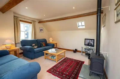 a living room with a blue couch and a wood stove at Cygnet Cottage in Keswick