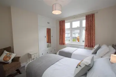 a bedroom with two beds and a chair and a window at Fell End in Keswick