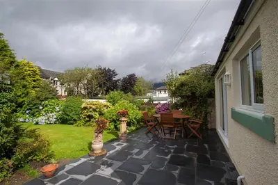 a patio with a table and chairs and flowers at Fell End in Keswick