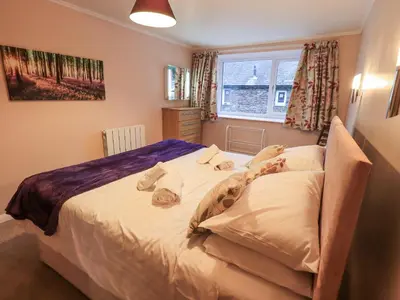 a bedroom with a large bed with white sheets at Molly's Cottage in Grasmere