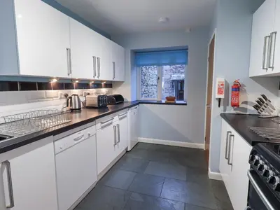 a kitchen with white cabinets and a window at Molly's Cottage in Grasmere