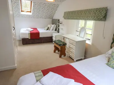 a bedroom with two beds and a dresser and a mirror at North Lodge in Grasmere