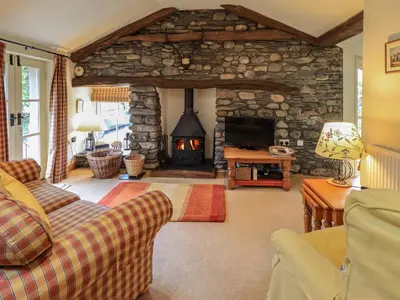 a living room with a stone fireplace and a couch at Beckside Studio in Patterdale