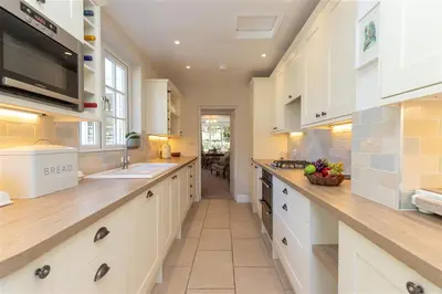 a large kitchen with white cabinets and a sink at Crozier Cottage in Ambleside