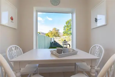 a white dining room table with chairs and a window at Crozier Cottage in Ambleside