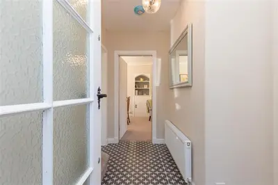 a hallway with a white door and a tile floor at Crozier Cottage in Ambleside