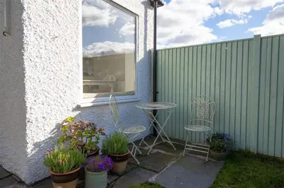 a patio with two chairs and a table and some plants at Crozier Cottage in Ambleside