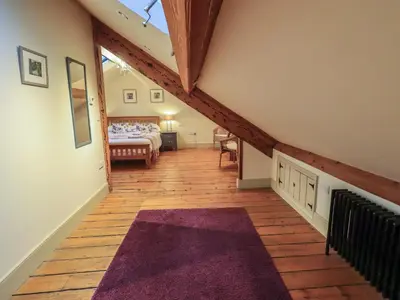 a attic hallway with a bed and a purple rug at Fairy Glen in Ambleside
