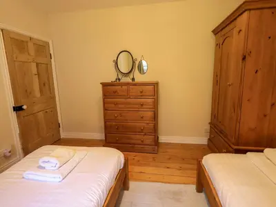 a bedroom with two beds and a dresser with a mirror at Daisy Cottage in Grasmere