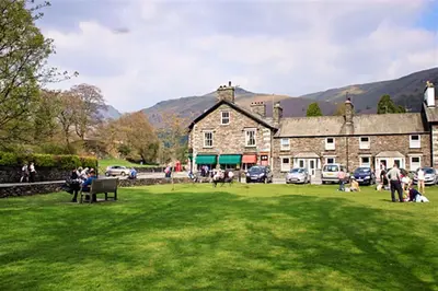 a group of people sitting in the grass in front of a building at The Gallery in Grasmere