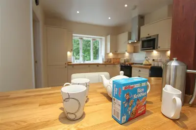 a kitchen table with a box of cereal and cups on it at Elterwater Lodge in Little Langdale