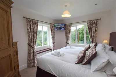 a bedroom with a large white bed with windows at Elterwater Lodge in Little Langdale