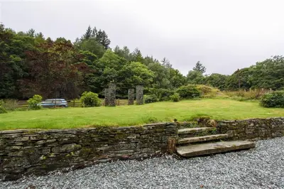 a stone retaining wall with a set of stairs at Elterwater Lodge in Little Langdale