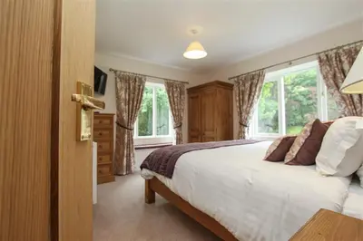 a bedroom with a large bed and windows at Elterwater Lodge in Little Langdale