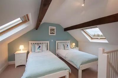 two beds in a attic room with two windows at Riggside in Keswick