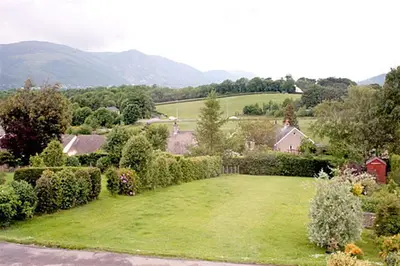 a garden with bushes and trees and a house at Riggside in Keswick