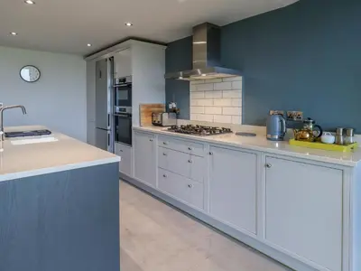 a large kitchen with white cabinets and a stove at Gillside in Keswick