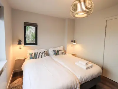 a bedroom with a large white bed with a chandelier at Gillside in Keswick