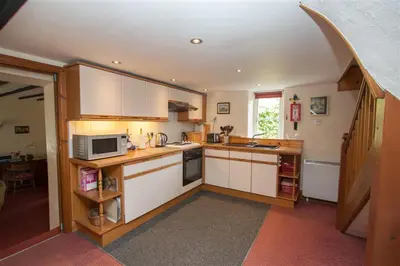 a kitchen with white cabinets and a microwave at Grisedale Cottage in Keswick