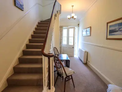 a staircase in a home with a table and a chair at Sandburne Cottage in Keswick